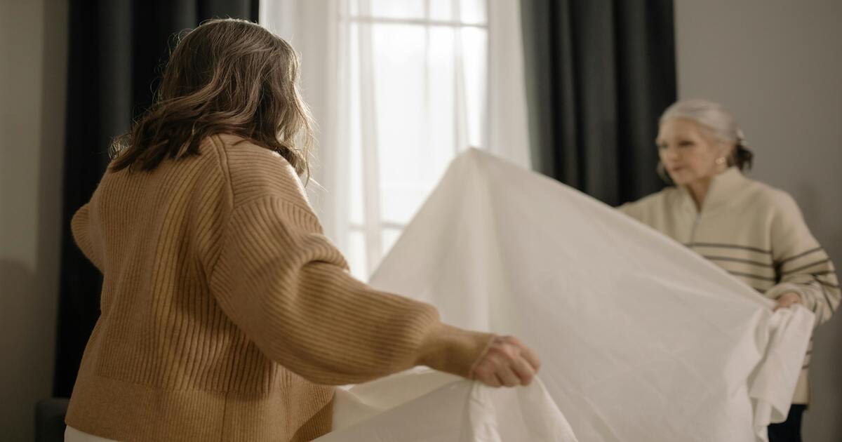 Two women attempting to determine sheet sizes in Australia.