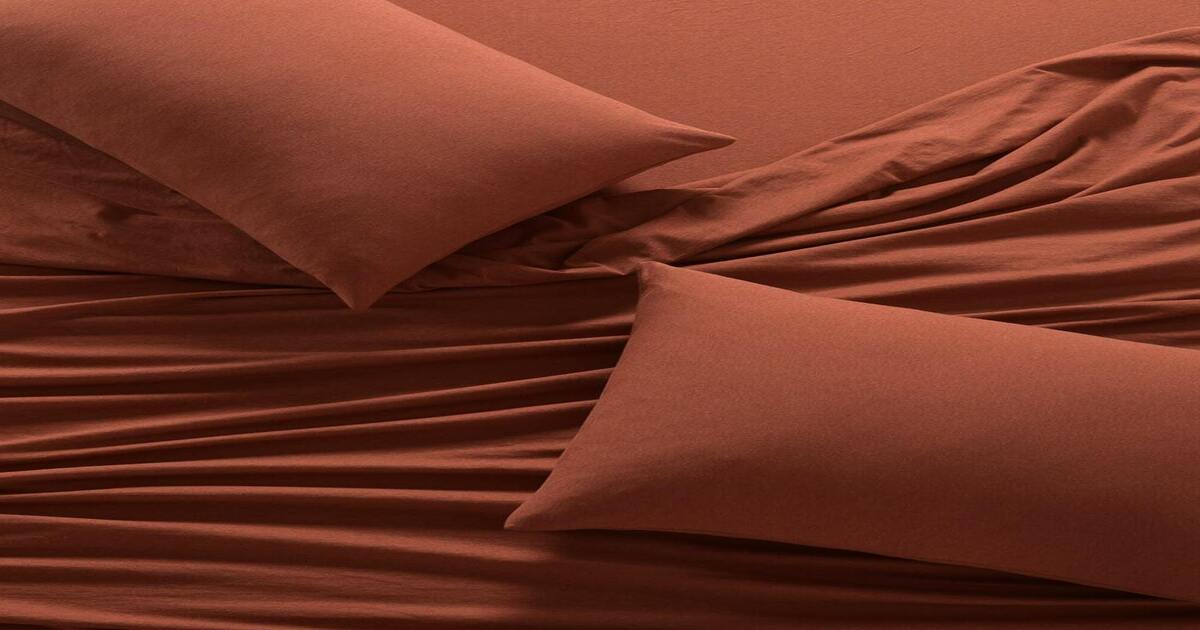 A close-up image of red jersey sheets and pillow protectors.